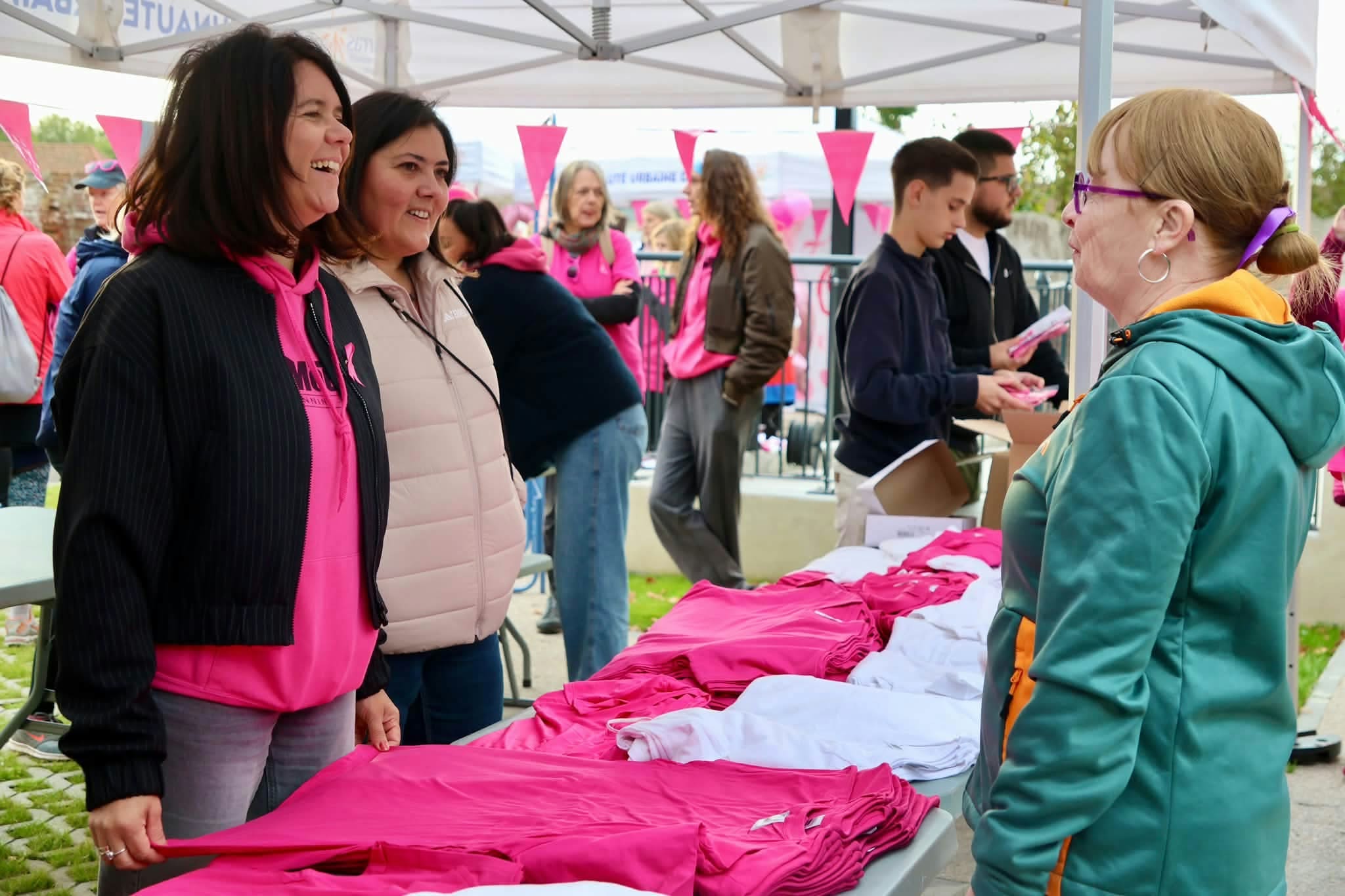 Empfang der Teilnehmenden und Ausgabe rosa T-Shirts unter einem Pavillon.