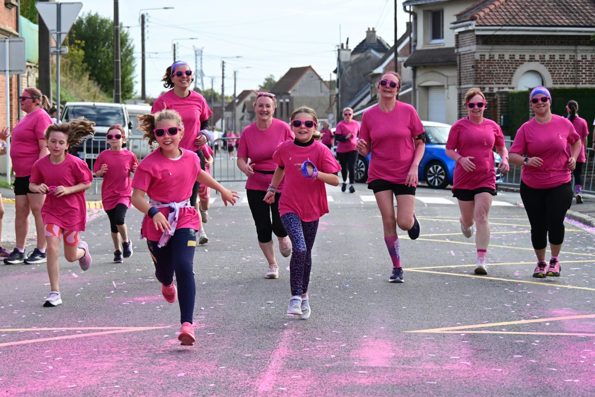 Erwachsene und Kinder laufen in rosa Kleidung durch Fampoux.