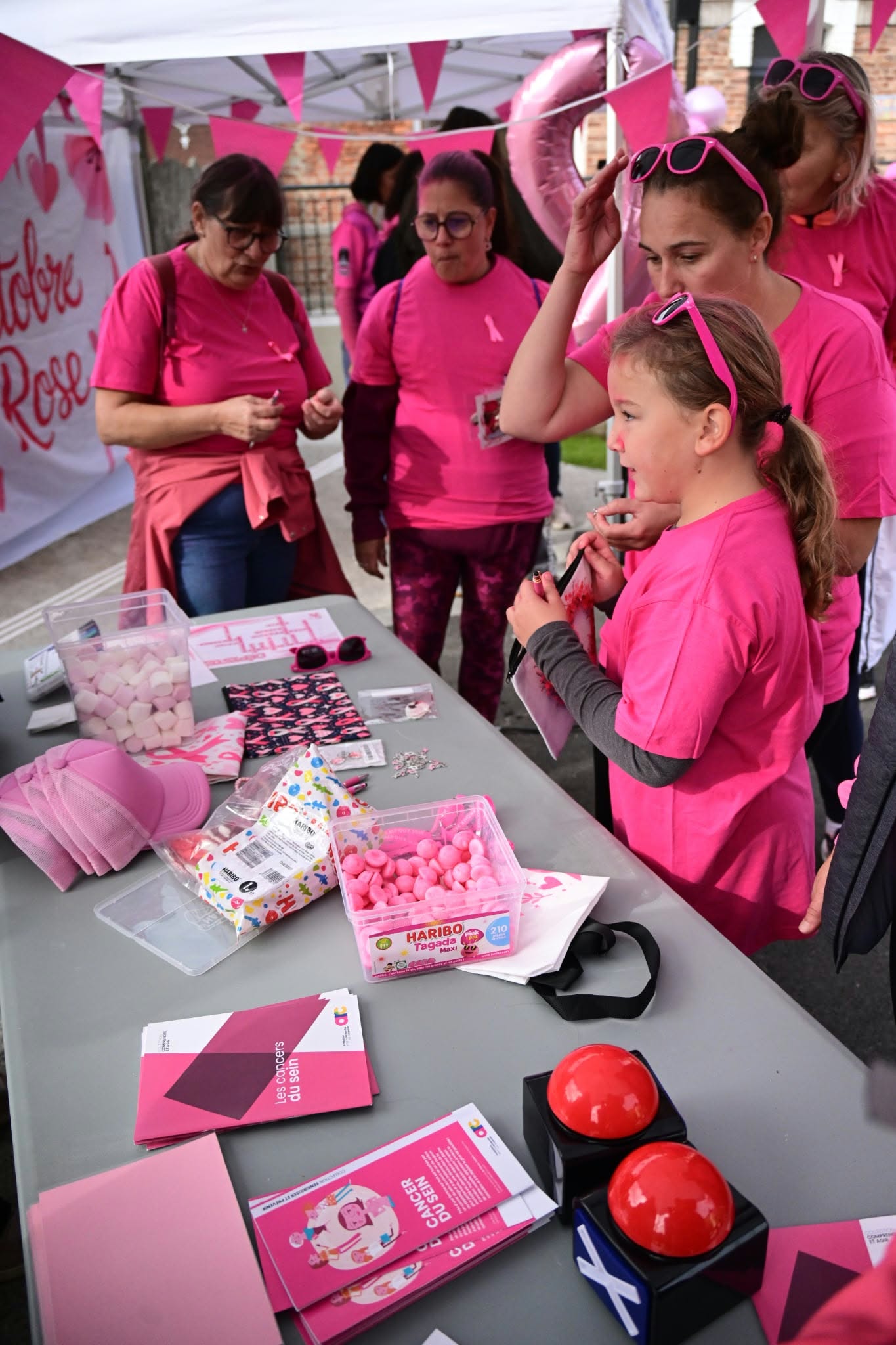 Ein Informationstisch zum Rosa Oktober mit Broschüren und rosa Accessoires.