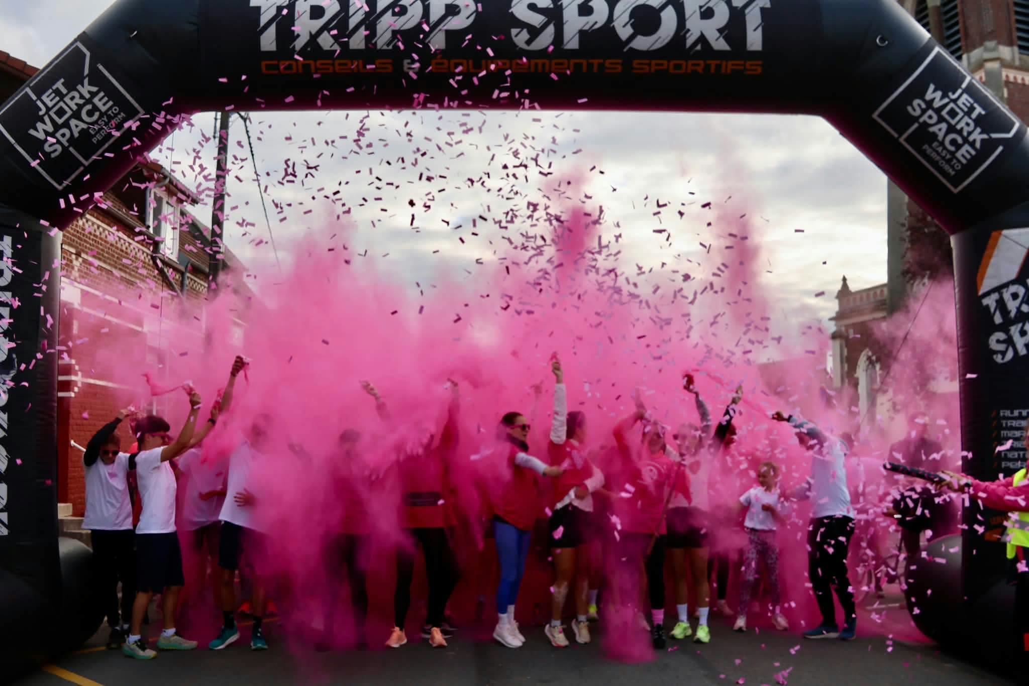 Die Gruppe unter dem TRIPP SPORT Torbogen zwischen rosa Farbpulver und Konfetti.